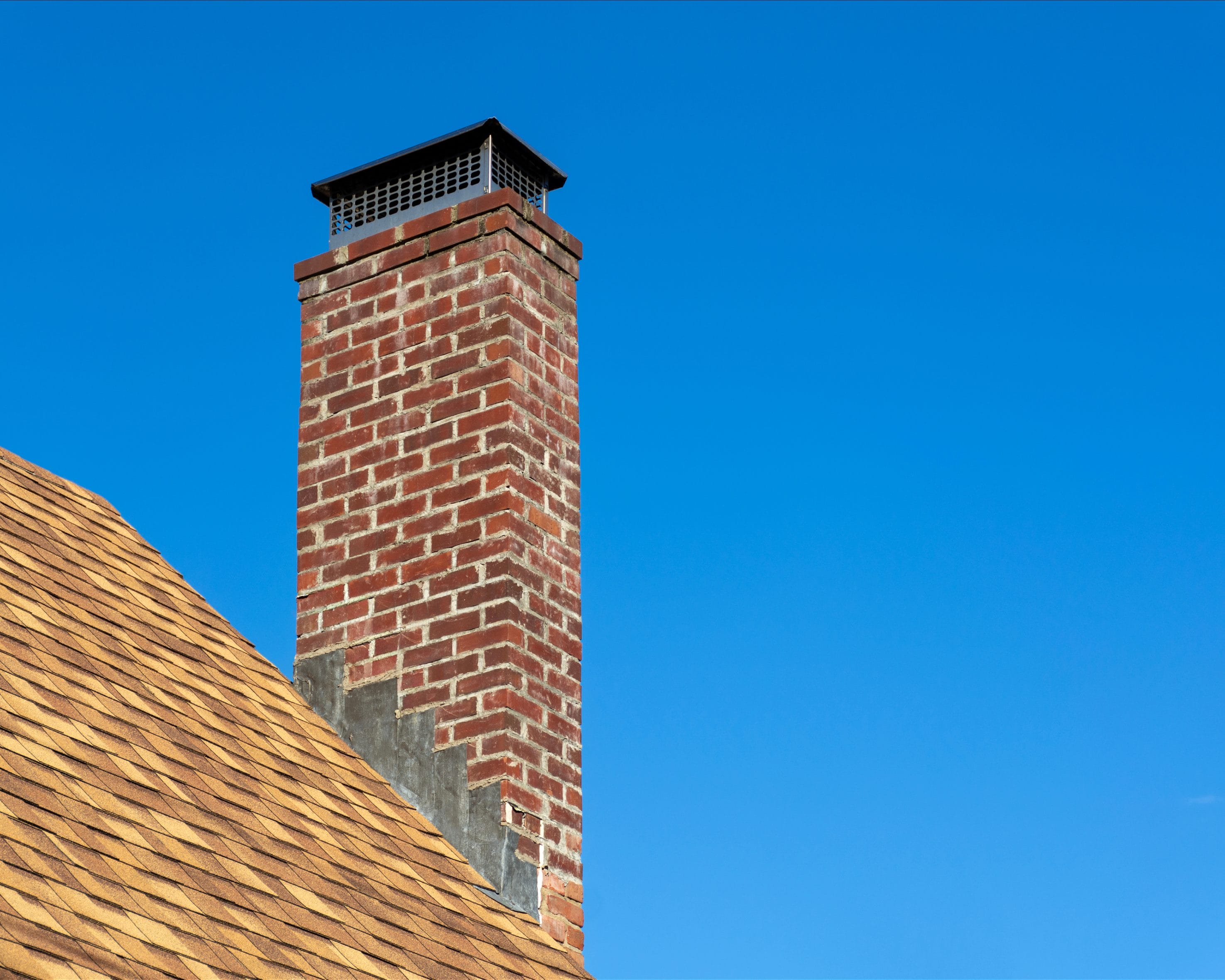A stock image of a chimney cap on top of a masonry chimney.
