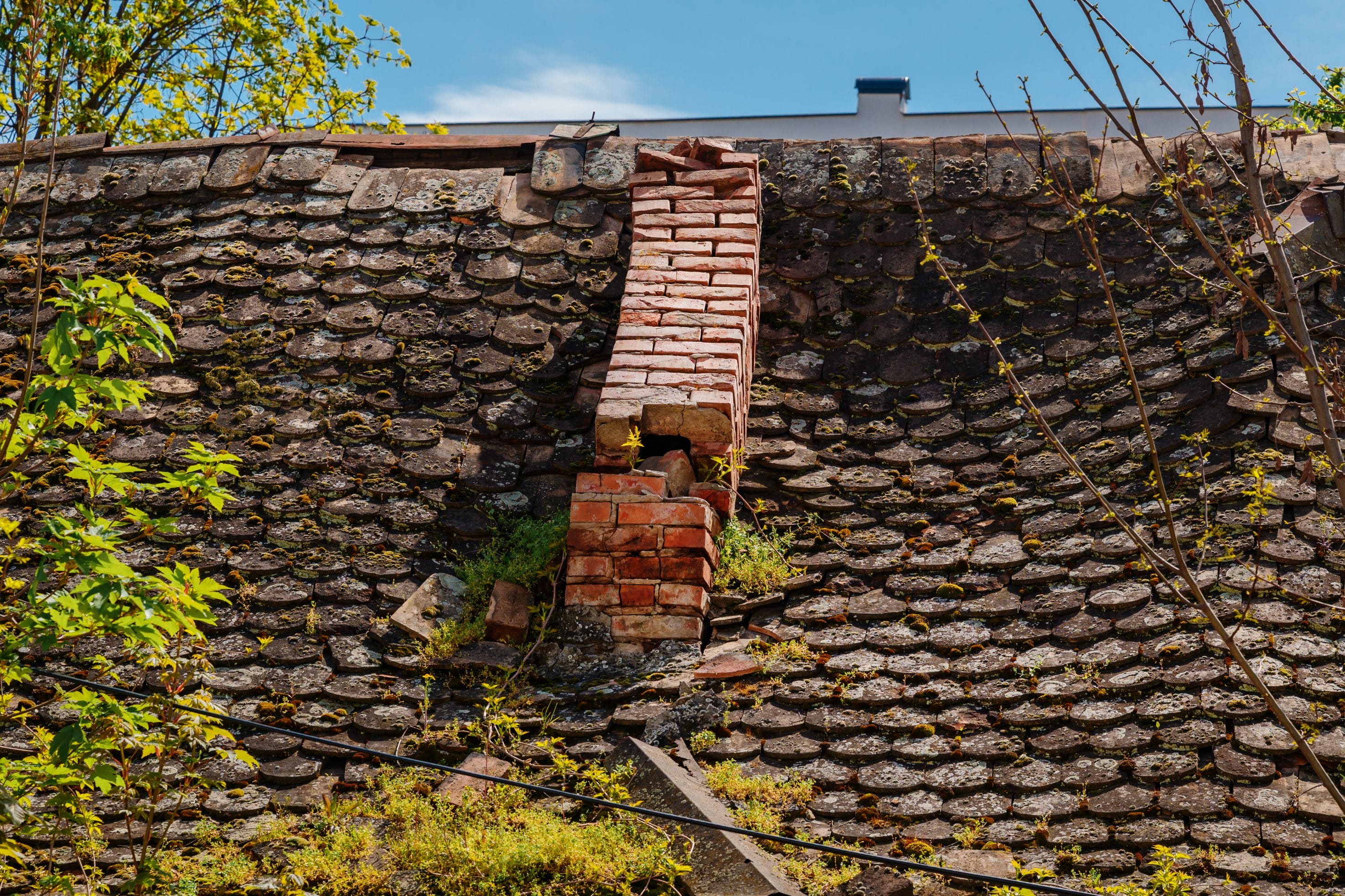 A stock image of a masonry chimney that has collapsed into a roof.