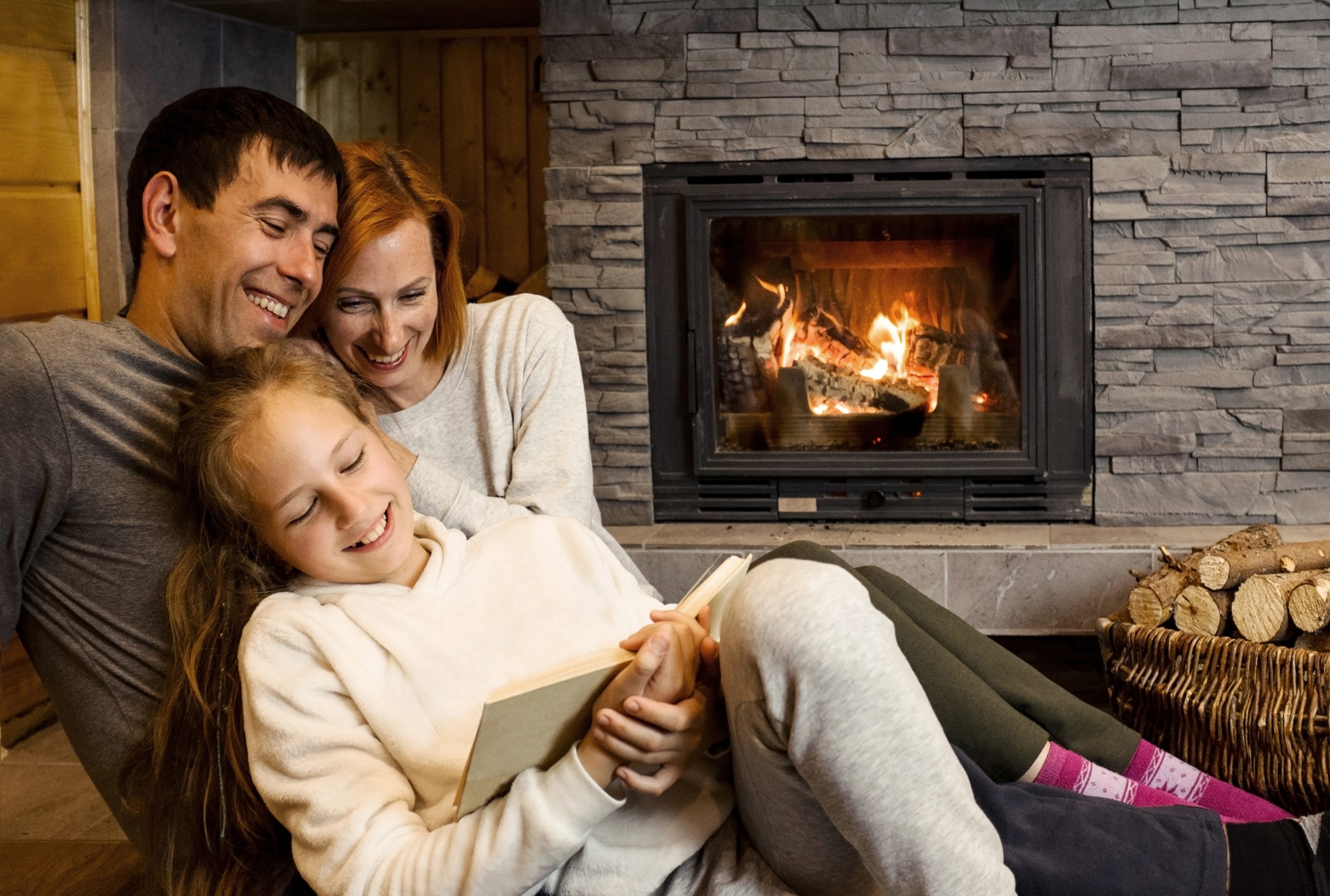 Stock image of a family relaxing by a brick wood fireplace.