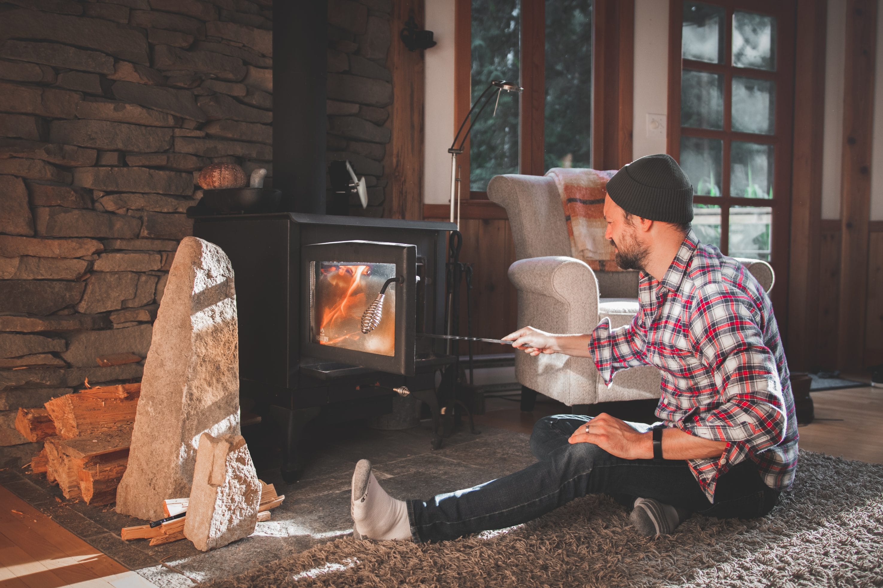 A stock image of man stoking a wood stove fire.